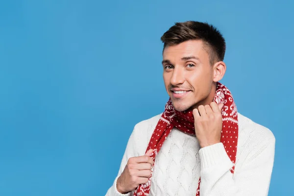 Positive man in sweater holding scarf isolated on blue — Stock Photo