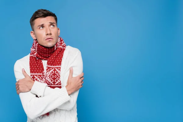 Молодий чоловік в шарфі страждає від холоду ізольовано на синьому — стокове фото