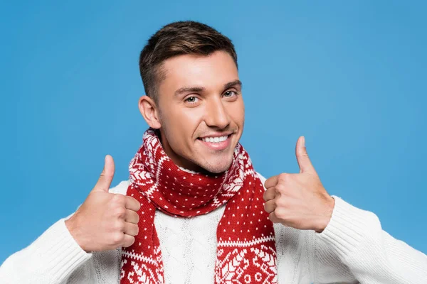 Fröhlicher Mann mit Schal zeigt Geste auf blauem Grund — Stockfoto