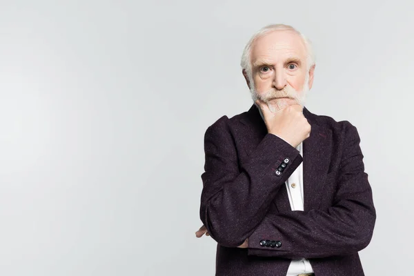 Thoughtful senior man in jacket looking at camera isolated on grey — Stock Photo