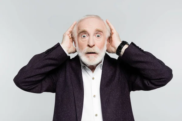 Surprised elderly man in jacket and shirt touching head isolated on grey — Stock Photo