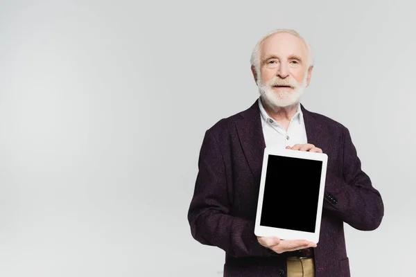 Hombre mayor sonriente sosteniendo tableta digital con pantalla en blanco aislada en gris - foto de stock
