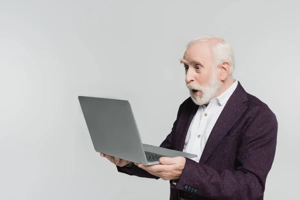 Choqué homme âgé regardant ordinateur portable isolé sur gris — Photo de stock