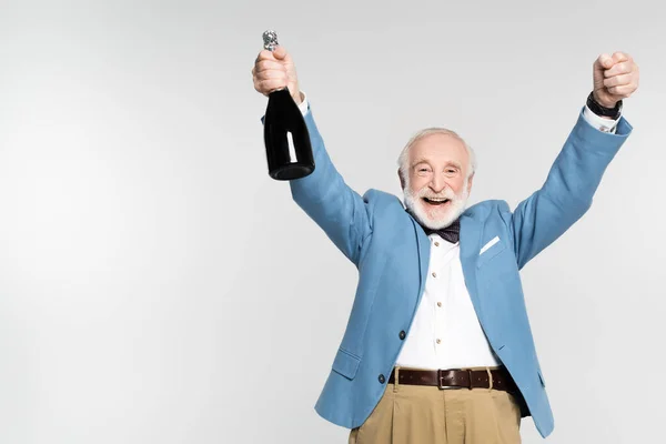Excited senior man holding bottle of champagne isolated on grey — Stock Photo
