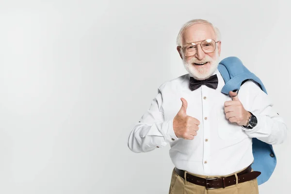 Älterer Mann lächelt in die Kamera, zeigt Daumen hoch und hält blaue Jacke isoliert auf grau — Stockfoto