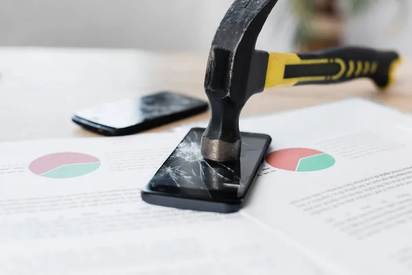 Close up view of hammer on damage touchscreen of smartphone with paper sheets on blurred background — Stock Photo