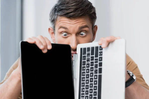 Surprised businessman looking at broken laptop on blurred background — Stock Photo