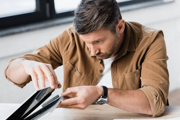 Homme d'affaires concentré réparer ordinateur portable endommagé tout en étant assis à la table sur fond flou — Photo de stock