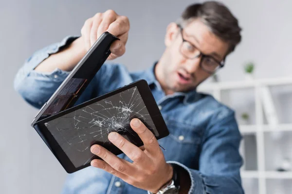 Surpris homme d'affaires démontage écrasé tablette numérique sur fond flou — Photo de stock
