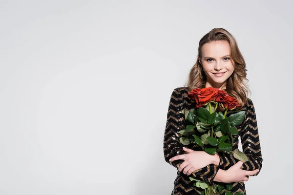 Heureuse jeune femme tenant bouquet de roses rouges sur gris — Photo de stock