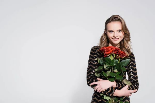 Feliz joven mujer sosteniendo ramo de rosas rojas en gris - foto de stock