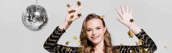 Cheerful young woman standing near disco ball and falling confetti on grey, banner — Stock Photo