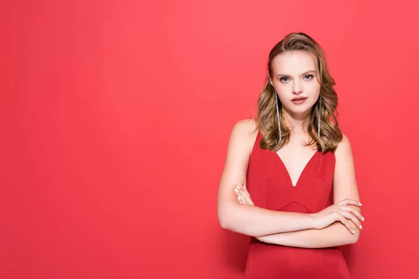 Young woman in dress standing with crossed arms on red — Stock Photo