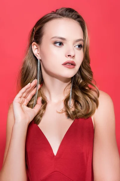 Jeune femme en boucles d'oreilles regardant loin sur rouge — Photo de stock