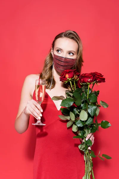 Junge Frau in Schutzmaske mit Strass, Rosen und einem Glas Champagner auf Rot — Stockfoto