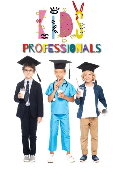 Children in graduation caps dressed in costumes of different professions holding glasses with milk near kids professionals lettering on white — Stock Photo