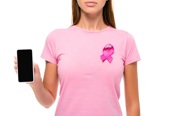 Cropped view of woman with pink ribbon of breast cancer awareness showing smartphone with blank screen isolated on white — Stock Photo