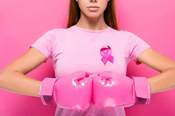 Vista cortada da jovem mulher em luvas de boxe rosa e fita de consciência do câncer de mama no fundo rosa — Fotografia de Stock