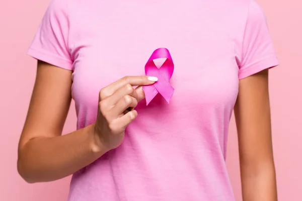 Обрезанный вид женщины, держащей символ информированности о раке молочной железы, выделенный розовым — стоковое фото