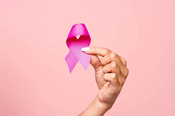 Cropped view of woman holding pink ribbon of breast cancer awareness isolated on pink — Stock Photo