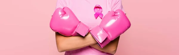 Обрізаний вид жінки в боксерських рукавичках і рожевий знак обізнаності про рак молочної залози ізольований на рожевому, банер — стокове фото