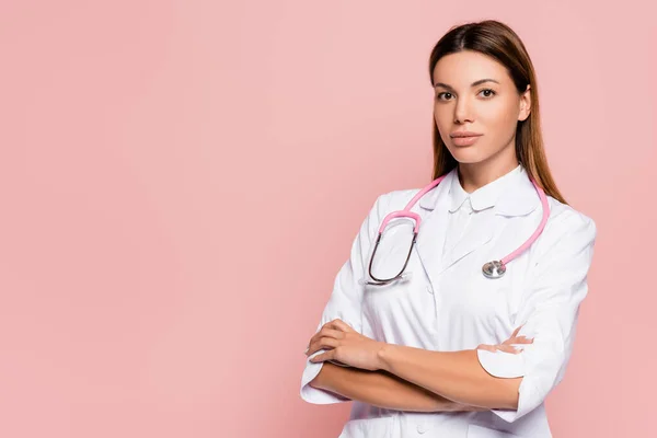 Junger Arzt in weißem Mantel und Stethoskop blickt isoliert auf rosa Kamera — Stockfoto