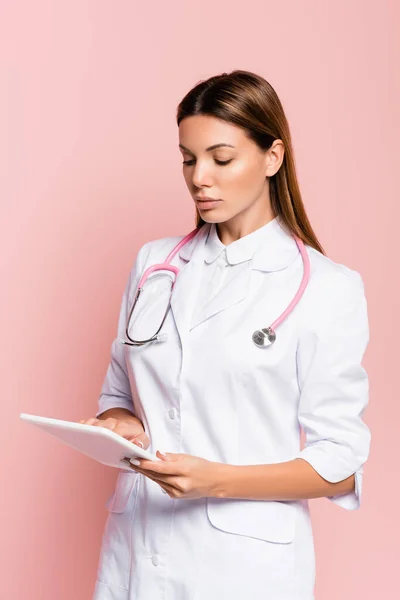 Médico com estetoscópio usando comprimido digital isolado em rosa — Fotografia de Stock