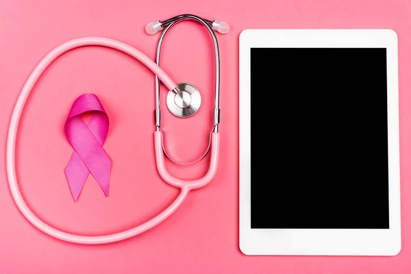 Top view of stethoscope, pink ribbon and digital tablet on pink surface — Stock Photo