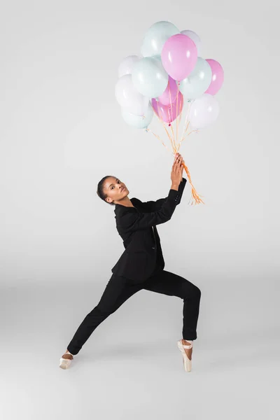 Donna d'affari afroamericana che esegue balletto con palloncini isolati su grigio — Foto stock