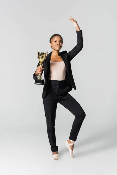 Femme d'affaires afro-américaine exécutant un ballet avec tasse dorée isolée sur gris — Photo de stock