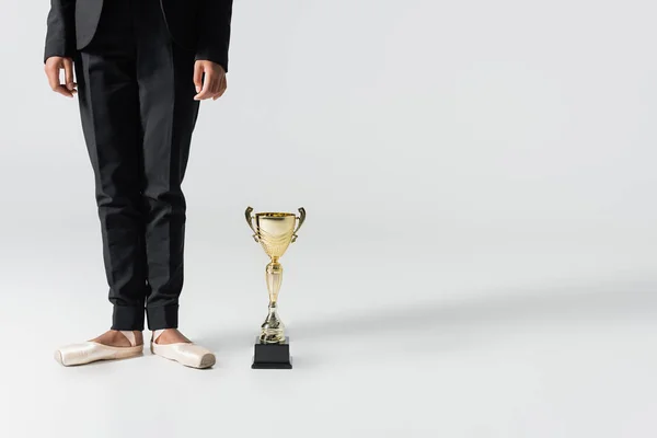 Cropped view of african american businesswoman in pointe shoes with golden cup on grey — Stock Photo