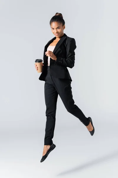 African american businesswoman performing ballet with paper cup isolated on grey — Stock Photo