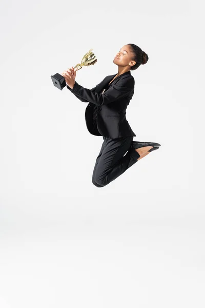 Афроамериканська бізнес-леді, що виконує балет із золотою чашкою ізольовано на сірому — стокове фото