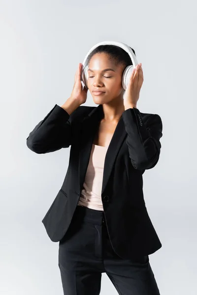 African american businesswoman listening music in headphones isolated on grey — Stock Photo