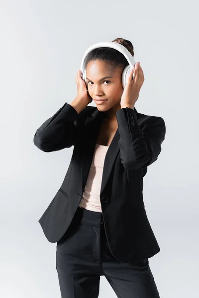 Empresaria afroamericana escuchando música en auriculares aislados en gris - foto de stock