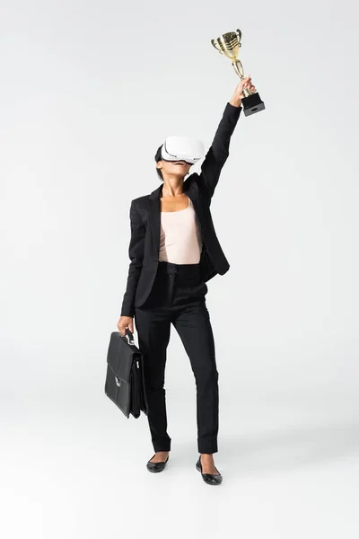 Mujer de negocios afroamericana con maleta y copa en auriculares vr aislados en blanco - foto de stock