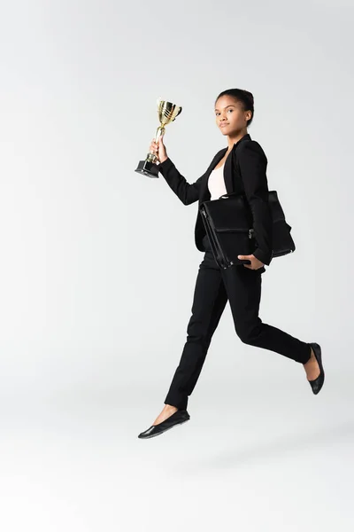 Side view of african american businesswoman with suitcase and goblet isolated on white — Stock Photo