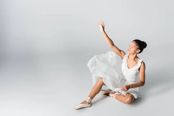 Graciosa bailarina afro-americana no vestido dançando no chão no fundo branco — Fotografia de Stock