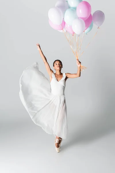 Graciosa bailarina afro-americana no vestido dançando com balões no fundo branco — Fotografia de Stock