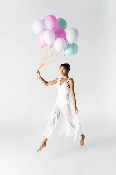 Barefoot graceful african american ballerina in dress with balloons on white background — Stock Photo