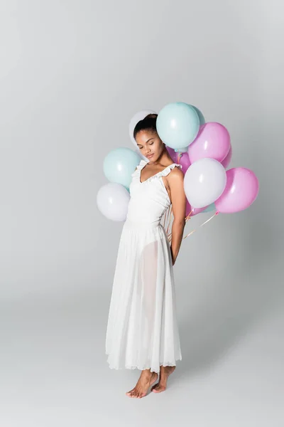 Barfuß anmutige afrikanisch-amerikanische Ballerina im Kleid mit Luftballons auf weißem Hintergrund — Stockfoto