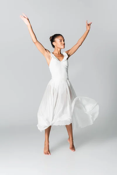 Descalza elegante bailarina afroamericana en vestido bailando sobre fondo blanco - foto de stock