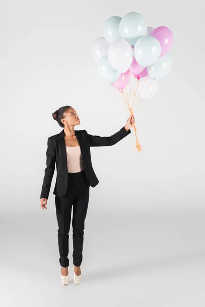 Donna d'affari afroamericana che esegue balletto con palloncini isolati su grigio — Foto stock