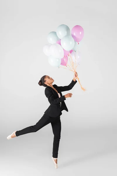 African american businesswoman performing ballet with balloons isolated on grey — Stock Photo