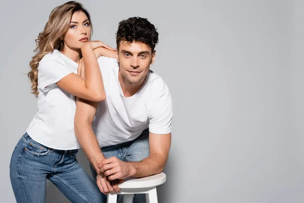 Jeune couple en t-shirts blancs câlins isolés sur gris — Photo de stock