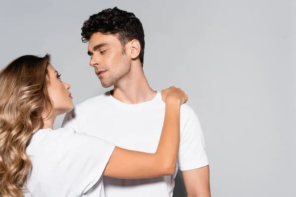 Jeune couple en t-shirts blancs câlins isolés sur gris — Photo de stock