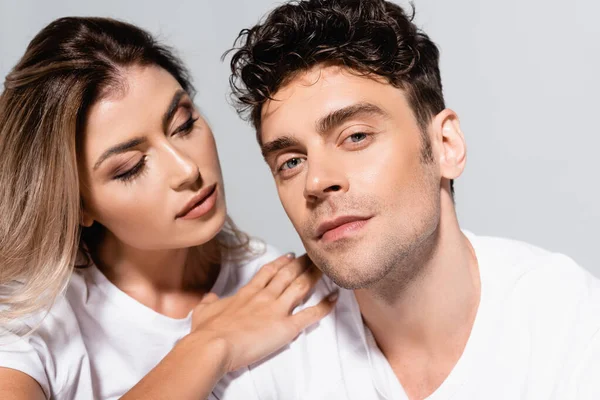 Jeune couple en t-shirts blancs embrassant isolé sur gris — Photo de stock