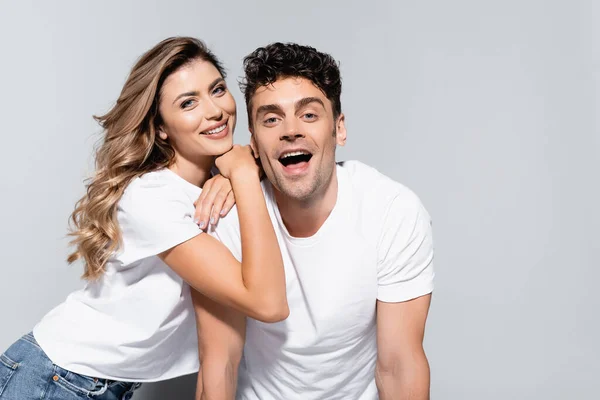 Feliz jovem casal em camisetas brancas posando isolado no cinza — Fotografia de Stock