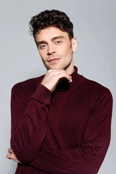 Young man in burgundy turtleneck jumper posing isolated on grey — Stock Photo