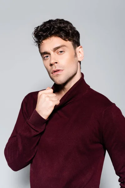 Giovane uomo in maglione dolcevita bordeaux in posa isolato sul grigio — Foto stock